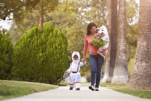 Parent Taking Children Trick Or Treating At Halloween